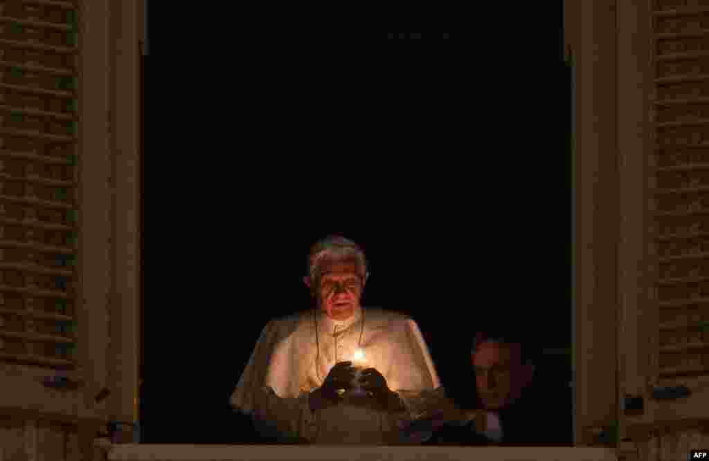 Pope Benedict XVI lights a candle in his private window at the end of a ceremony unveiling the crib on St Peter&#39;s Square in the Vatican on December 24. (AFP/Andreas Solaro)