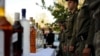Иранские полицейские стоят напротив стола с конфискованным алкоголем.