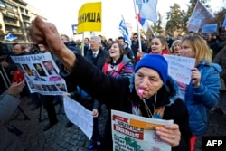 An elderly woman blows a whistle as protesters march during an antigovernment protest in Belgrade on February 15.