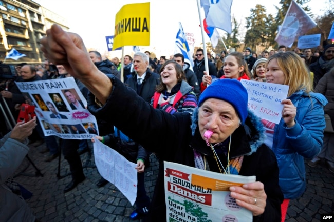 An elderly woman blows a whistle as protesters march during an antigovernment protest in Belgrade on February 15.