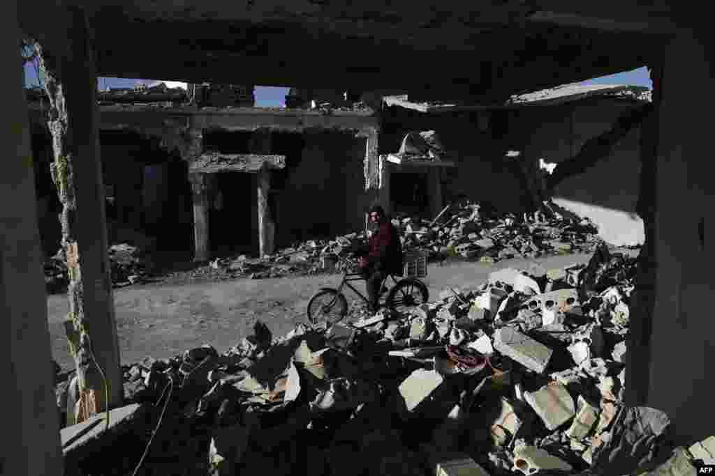 A Syrian man rides his bicycle past the rubble of destroyed buildings in the rebel-held town of Douma, on the outskirts of the capital, Damascus. (AFP/Sameer al-Doumy)