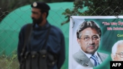 Pakistan -- A policeman stands guard next to a banner showing an image of former military ruler Pervez Musharraf near his residence in Islamabad, November 6, 2013