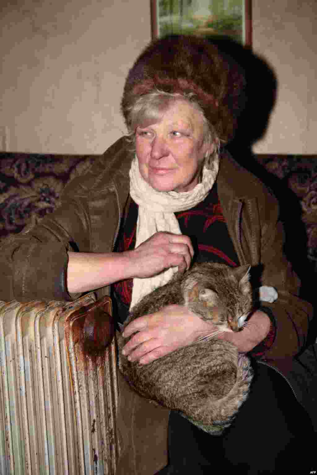 Жінка з котом гріється біля електричної батареї. Донецьк, 10 січня 2014 року