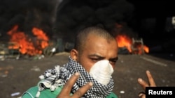 A protester gestures in front of a burning barricade during demonstrations in Cairo on January 28.