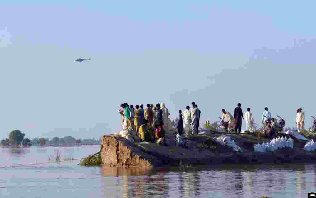 Pakistani villagers gather on higher ground as floodwaters enter the Hafizabad district of Punjab Province.