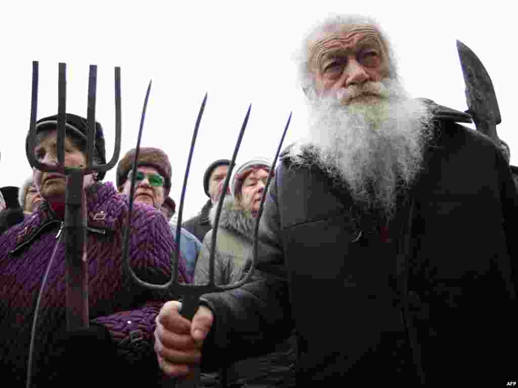 Protesters hold pitchforks and spades during a rally in front of the city administration building in Donetsk, Ukraine, on November 28 in support of demands by World War II and Afghan war survivors as well as Chornobyl cleanup crews. (AFP Photo/Alexander K