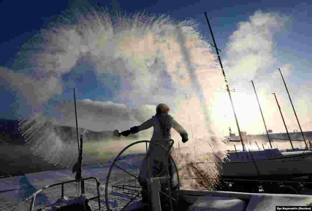 A member of the Skipper yacht club dressed as Snegurochka (Snowmaiden) slops over hot water during an event dedicated to the end of the sailboat season, with the air temperature at about minus 33 degrees Celsius outside the Siberian city of Krasnoyarsk on December 5. (Reuters/Ilya Naymushin)