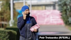 Женщина говорит по телефону на улице в Алматы.
