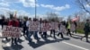 Demonstranti u Novom Sadu protestuju zbog hapšenja aktivista čija imena nose na čelu kolone, 12. aprila 2025. godine. 