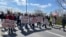 Demonstranti u Novom Sadu protestuju zbog hapšenja aktivista čija imena nose na čelu kolone, 12. aprila 2025. godine. 