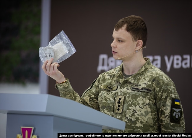 Andriy Rudyk, përfaqësues i Qendrës ukrainase për Kërkim mbi armët e avancuara ushtarake, duke mbajtur në dorë pjesë të granatës ruse, RG-Vo.
