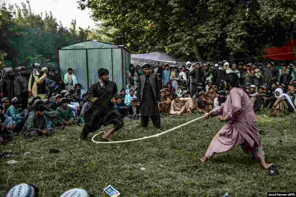 Men watch people playing a traditional Afghan rope game called dora in a field in a Taliban stronghold in Kandahar Province, despite the spread of the coronavirus in the country. The Taliban boasted of its readiness to fight the virus when it first reached Afghanistan, but now the insurgents are struggling to curb its spread in their strongholds. (AFP/Javed Tanveer)