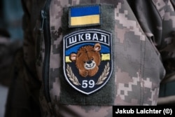 A female convict soldier with a version of the Shkval battalion emblem.