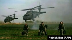 FILE: U.S. army special forces walk in a field as Blackhawk helicopters transporting NATO officers land in Marjah's Balakino Bazar neighborhood in 2010.