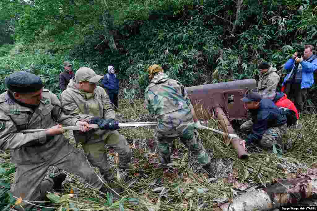 Members of the expedition, which was organized by the Russian Geographical Society and the Russian Defense Ministry, haul an artillery piece from the jungle of Iturup. The photo was released by the TASS news agency on August 19.