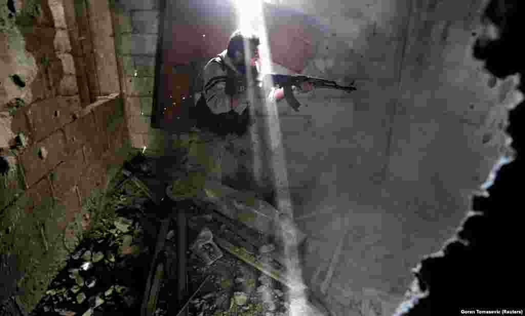 A rebel fighter fires through a hole in a wall at Syrian army soldiers in January 2013. In a Reuters interview the veteran war photographer said that "when a combat situation starts for me there is no way back.... I would be ashamed of myself for not going to the end."