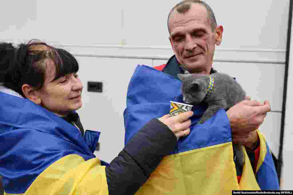 Оксана та Валерій, евакуйовані під час гуманітарної місії з окупованих Росією Олешок, годують свого кота Боцмана