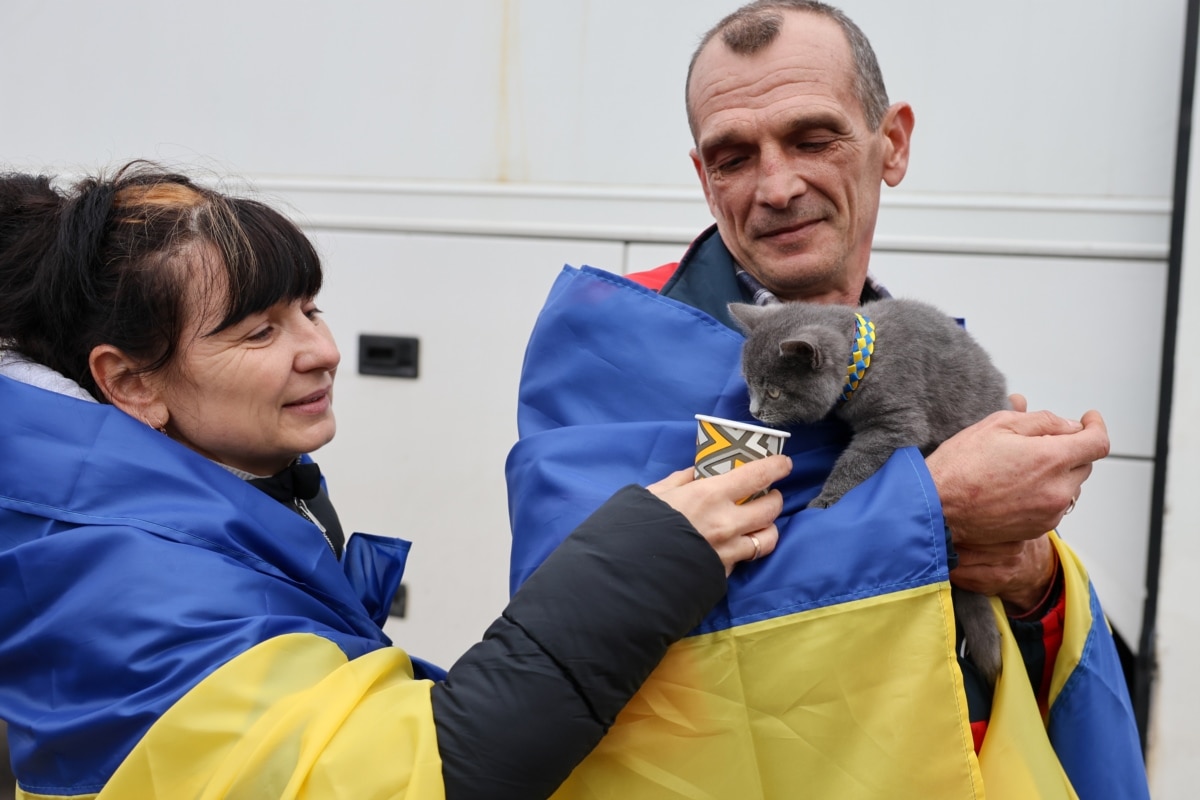 Оксана та Валерій, евакуйовані під час гуманітарної місії з окупованих Росією Олешок, годують свого кота Боцмана