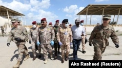 Iraqi Army officers wear protective masks, following the outbreak of coronavirus disease (COVID-19), as they walk with U.S. officers before a handover ceremony of K-1 airbase from U.S.-led coalition forces to Iraqi Security Forces. March 29, 2020