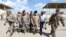 Iraqi Army officers wear protective masks, following the outbreak of coronavirus disease (COVID-19), as they walk with U.S. officers before a handover ceremony of K-1 airbase from U.S.-led coalition forces to Iraqi Security Forces. March 29, 2020