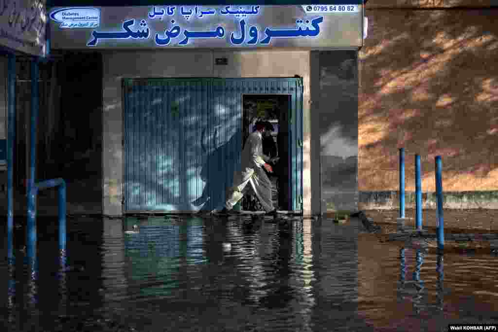 An Afghan man walks through a waterlogged street after heavy rainfall in Kabul.&nbsp;