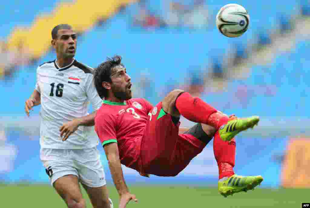 Iraq&#39;s Ali Bahjat Fadhil Fadhil (left) looks on as Tajikistan&#39;s Siyovush Asrorov eyes the ball in their men&#39;s round of 16 football match during the 17th Asian Games at Incheon Football Stadium in Incheon, South Korea. (AFP/Al-Watan Doha/Karim Jaafar)