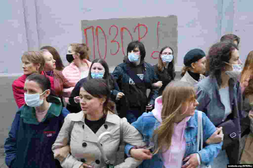 Protesters link arms in front of a wall where the word &quot;SHAME!&quot; has been written.&nbsp;