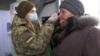 Українська військова перевіряє температуру літньої жінки на пункті пропуску в Майорську Донецької області