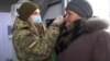 Українська військова заміряє температуру жінці при перетині пункту в’їзду-виїзду в Майорську, Донецька область, 16 березня 2020 року