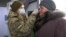 A Ukrainian soldier checks the temperature of an elderly woman at a checkpoint in Mayorsk in the Donetsk region last month.