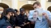 Policajka legitimiše muškarca koji drži plakatu sa likom Aljekseja Navaljnija, opozicionog lidera koji je u bolnici u sibirskom gradu Omsku, na protestu u Sankt Petersburgu. 20. avgust 2020.