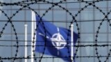 Belgium -- The NATO flag is seen through barbed wire as it flies in front of the new NATO Headquarters in Brussels, May 24, 2017