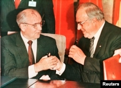 Liderul sovietic Mihail Gorbaciov (stânga) și cancelarul german Helmut Kohl fac schimb de stilouri după ce au semnat un contract la Bonn, în noiembrie 1990.