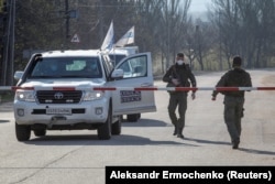 Автомобіль місії ОБСЄ у пункті пропуску Майорськ з боку окупованої території у 2020 році. Люди у формі – це бійці підконтрольного Росії угруповання «ДНР»