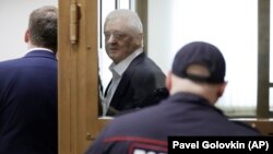 Frode Berg speaks with his lawyer from inside a glass cage in a courtroom in Moscow on April 16.