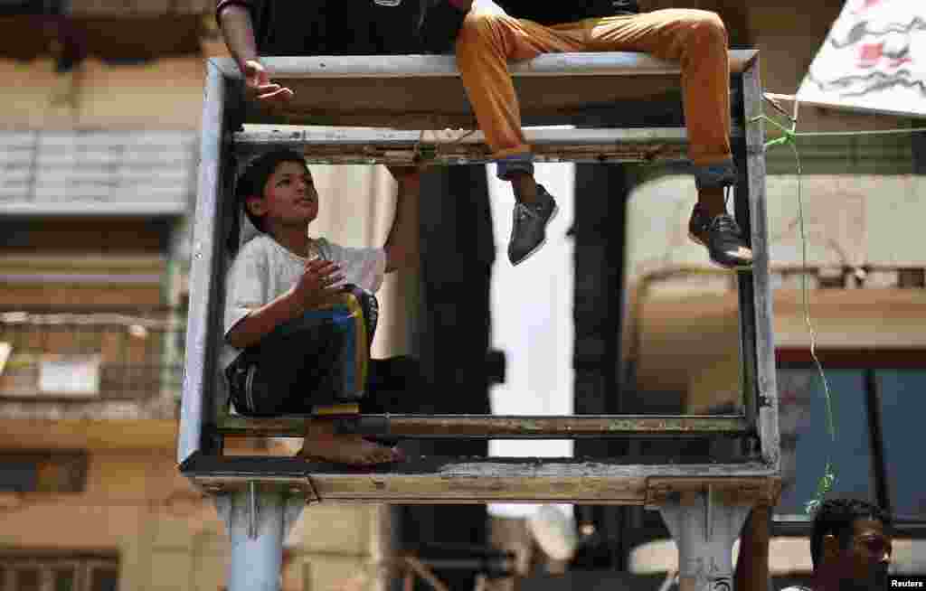A boy sits inside a frame box for banner advertisements during a protest at Tahrir Square.