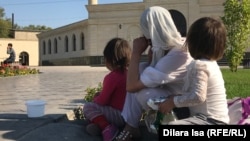 Aýal çagalary bilen metjidiň öňünde oturyp, sadaka soraýar. Şymkent. Oktýabr. 2019.