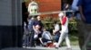 A person is treated by emergency workers as members of the Republican congressional baseball team look on following a shooting in Alexandria, Virginia, on June 14. 
