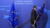 An employee at the EU council in Brussels on November 22 adjusts European Union flags at the entrance of the council headquarters for an EU leaders' summit discussing the bloc's long-term budget.