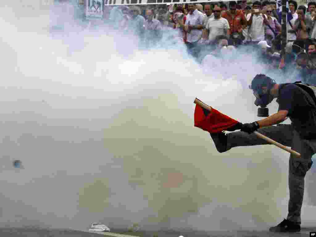 Manifestant grec, îndepărtând cu piciorul o grenadă cu gaze lacrimogene, în timpul protestelor violente din faţa Parlamentului de la Atena ţinute împotriva noilor măsuri de austeritate, 15 iunie.Kostas Tsironis for AP