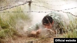 Участник международных соревнований «Алтын Уки — 2015» для спецподразделений ползет под заграждением из колючей проволоки. Спасск, 2 июля 2015 года.