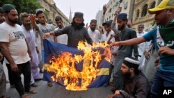 Në Pakistan u dogj flamuri i Suedisë, për shkak të djegies së Kuranit nga disa aktivistë suedezë. Korrik, 2023.