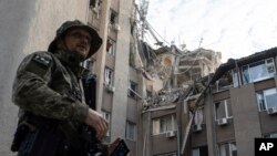 Ukrajinski vojnik ispred zgrade koja je teško oštećena u ruskom vazdušnom napadu u Hersonu 15. juna 2023.