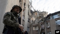 Ukrán katona egy orosz légicsapásban súlyosan megsérült épület előtt Herszonban 2023. június 15-én