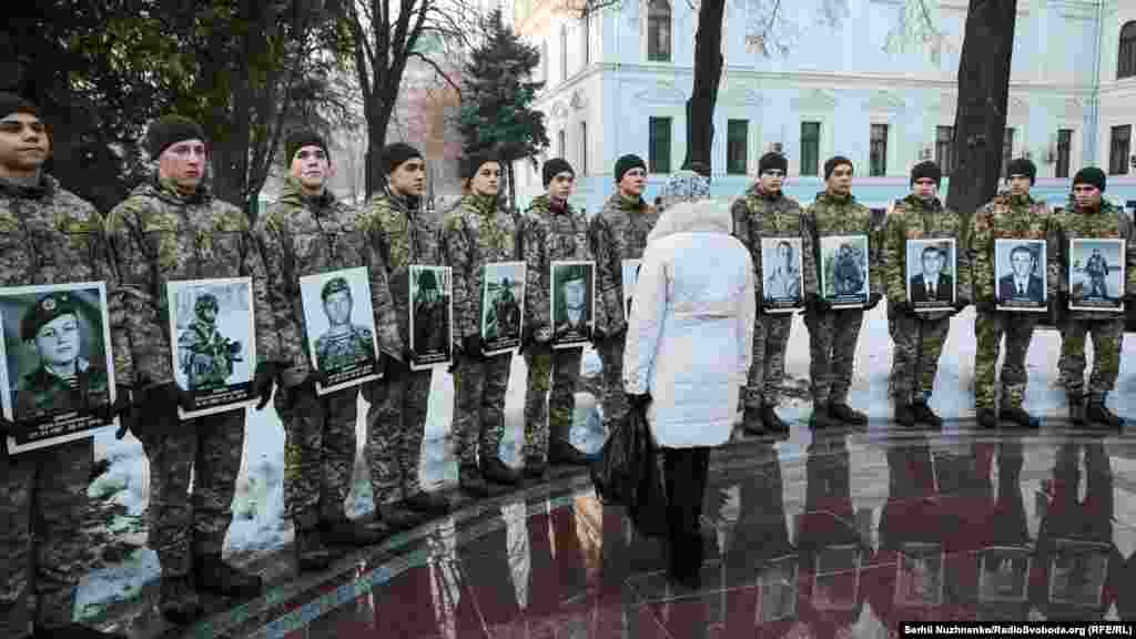 Жінка дивиться на портрети загиблих оборонців Донецького аеропорту