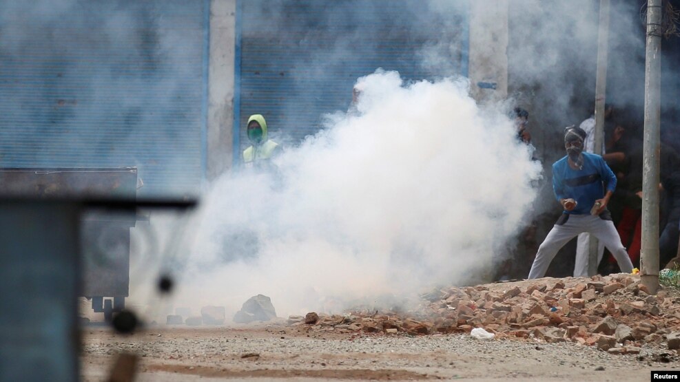 Pamje e protestuesve në Kashmir duke gjuajtur gurë mndaj policëve që kishin hedhur gaz lotsjellës