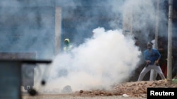 Protesters throw stones amid tear gas smoke fired by Indian police during a protest against the killing of Burhan Wani on July 10.