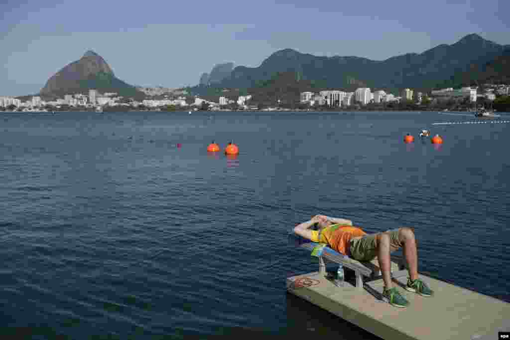 A worker at the Lagoa venue waits out a weather delay for rowing events caused by strong winds.