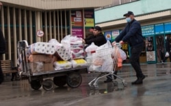 Мужчина толкает тележку с продуктами и туалетной бумагой в районе Зеленого базара. Алматы 18 марта 2020 года.