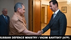 A file photo of Russian Defense Minister Sergei Shoigu (left) shaking hands with Syrian President Bashar al-Assad during a meeting in Damascus in 2016.